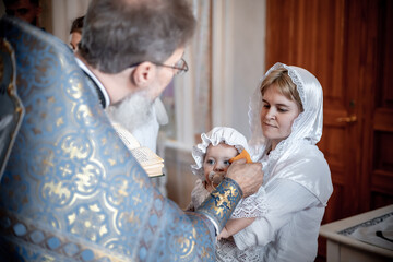 anointing of a small child in an Orthodox Christian church or temple during the sacrament of...