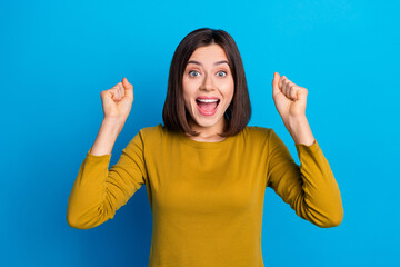 Photo of adorable lucky woman wear shirt rising fists screaming yeah isolated blue color background