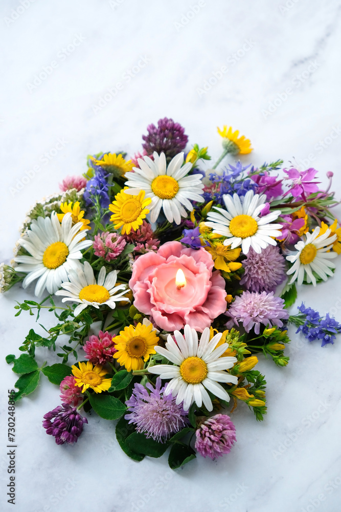 Wall mural flower shape candle with colorful meadow flowers on abstract marble background close up. esoteric ri