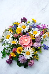 flower shape candle with colorful meadow flowers on abstract marble background close up. esoteric...