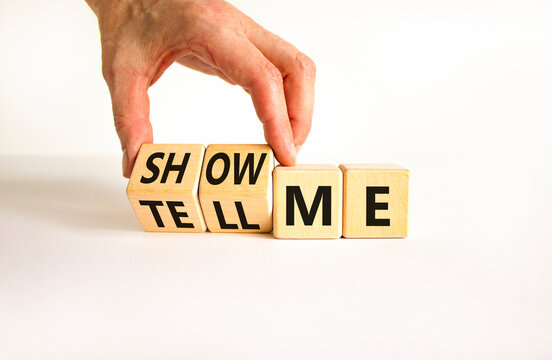 Tell or show me symbol. Businessman turns beautiful wooden cubes and changes words Tell me to Show me. Beautiful white table white background. Business tell or show me concept. Copy space.