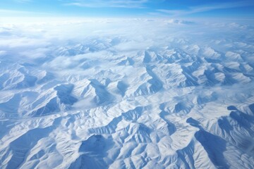 Fototapeta na wymiar Aerial view of a mountainous terrain covered in a blanket of snow