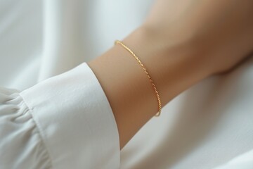 Thin gold bracelet on a woman's hand in a white blouse. Quiet luxury concept. - obrazy, fototapety, plakaty