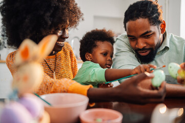 Close up of interracial family sits together at easter and painting eggs.