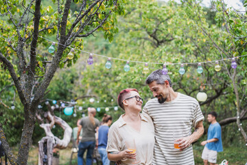 Young mature adult romantic hipster couple spending time hugging during a garden party at suumer. Love concept