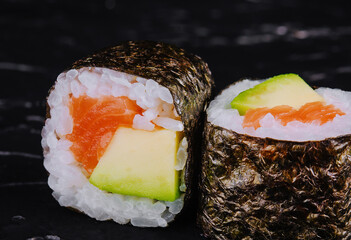 Sushi rolls with salmon and avocado on a black stone