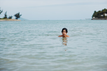 Swim In the Blissful Beauty: An Asian Man's Joyful Vacation amidst the Tropical Ocean, Embracing the Freedom of a Refreshing Splash of Water on a Sunny Summer Day