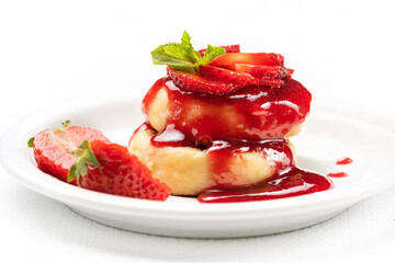 Pancakes from cottage cheese on a plate decorated with strawberry jam and fresh ripe strawberry slices on a white background. Summer time. Healthy food