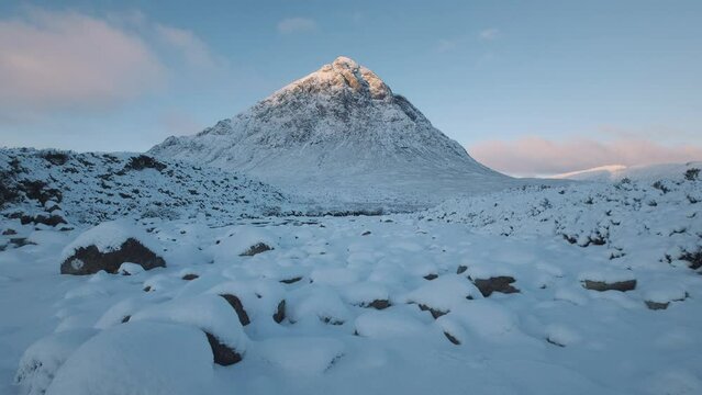 4k footage of the snowcapped Buachaille Etive Mor mountain and the frozen Coe River at sunrise. Scottish Highlands, UK. 