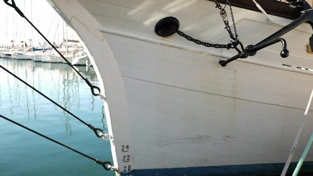 Bow of an old boat with peeling paint that floats on water on pier, swinging on waves, side view,