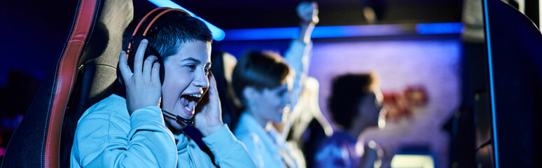 focus on cheerful young woman winning game next to diverse female friends, cybersport gamers banner