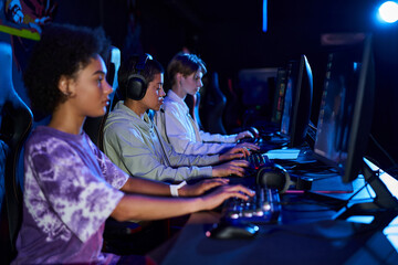 Diverse interracial women zoomers engaged in cybersport games, using computers and headphones