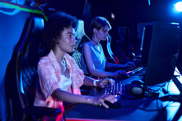 Fototapeta na wymiar focus on young african american woman gaming intensely in a blue-lit room, cybersport concept