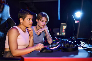 Two women with tattoos concentrating on a cybersport game in computer club room, female gamers © LIGHTFIELD STUDIOS