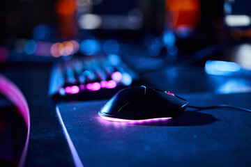 close up of illuminated computer mouse near computer keyboard, cybersport and gaming accessories