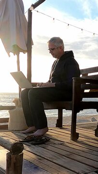Remote working from the beach at sunset. Vertical format