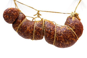 Traditional smoked sausage hanging on ropes on white background.