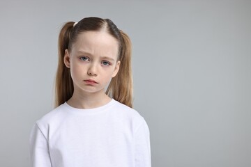 Fototapeta premium Portrait of sad girl on light grey background, space for text