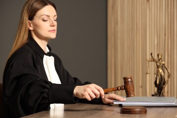 Judge striking mallet at wooden table in courtroom, selective focus. Space for text