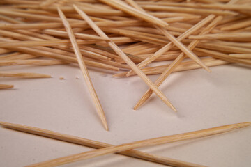 Many small toothpicks or wooden skewers lie disorganized on a white table
