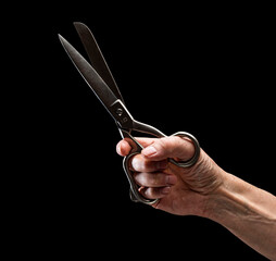 Opened old metal fabric scissors in a man's hand on a black background.