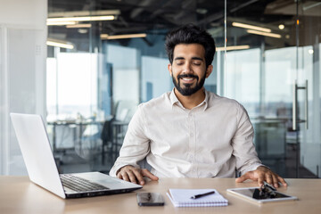 Fototapeta na wymiar Confident indian businessman in office, working on laptop at modern desk