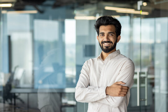 Confident indian businessman smiling in modern office setting, corporate professional portrait