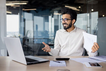 Confident indian businessman in office working on laptop with a warm smile