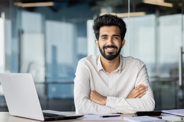 Confident indian businessman with beard working at office desk with laptop