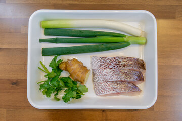 バットに並べられた魚や野菜などの家庭料理の食材