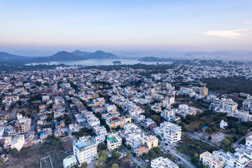 Aerial drone shot over udiapur, jaipur, kota,, cityscape with homes, houses, buildings and aravalli hills and lakes in the distance hidden in fog