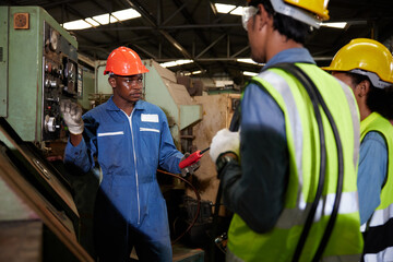male african foreman training and teaching how to use machine control with workers in factory