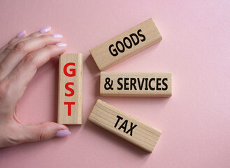 GST - Goods and Services Tax symbol. Concept word GST on wooden blocks. Businessman hand. Beautiful...
