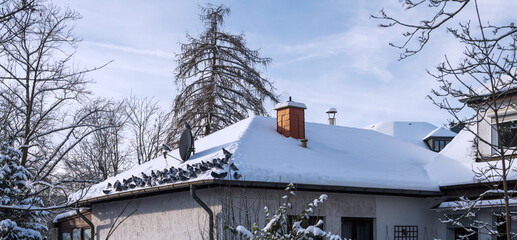 Schnee auf Hausdach mit vielen Tauben die dort sitzen