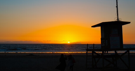Lifeguard tower under an orange sky at sunset in Los Angeles