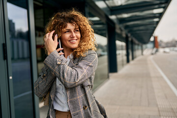 A successful and pretty businesswoman, dressed in casual attire, exits the railway station with...