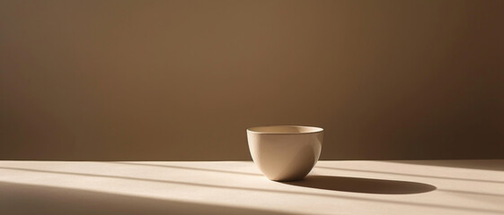 The stark simplicity of a ceramic bowl, its shadow casting long lines across a minimalist surface