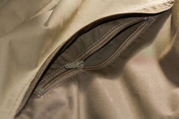 Zipper on beige workwear protective clothing in close-up.