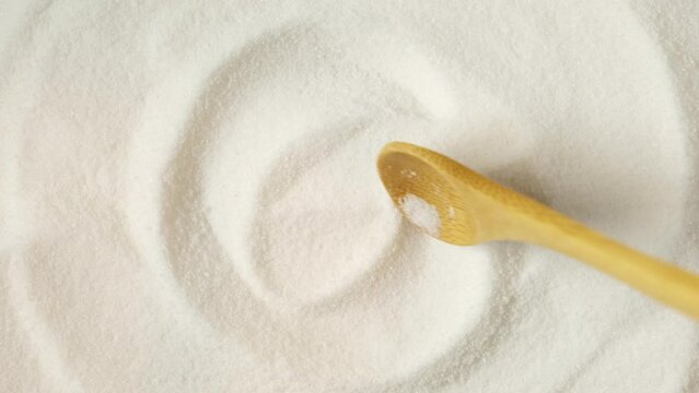Pile of gluconolactone, close-up. Glucono Delta-Lactone, Pure GDL and wooden spoon. White powder, oxidized derivative of glucose. Texture of food additive E575. 4K video.