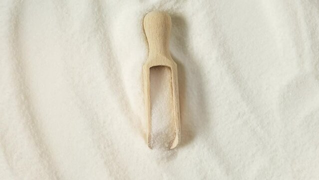Pure GDL, white odorless crystalline powder in wooden spoon. Food additive E575 used as acidity regulator or leavening agent. Gluconolactone or Glucono Delta-Lactone. 4K video, rotating.
