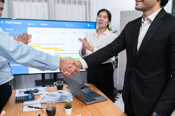Cheerful meeting room, businesspeople celebrate with handshaking. Successful project was completed...