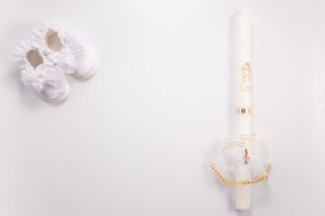 Christening background with baptism baby shoes and candle on white background