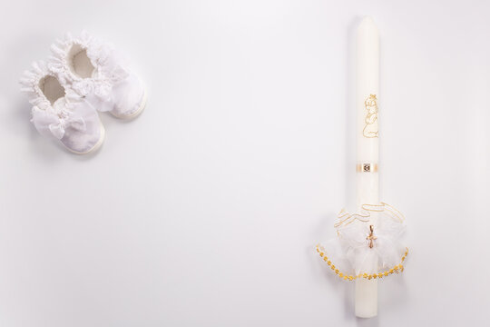 Christening background with baptism baby shoes and candle on white background
