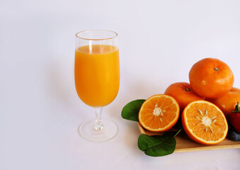 Orange juice in a glass Place the fruit and halves on a wooden tray on a white background.

