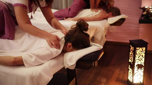 Hands of woman doing neck massage for girl and female hands doing massage for man in thai massage salon, slow motion
