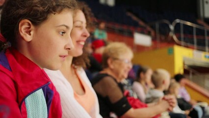 Pretty girl, mother smiles and shows at stage out of focus in circus, slow motion