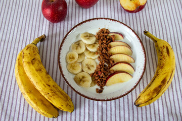 Zdrowe śniadanie z jogurtem naturalnym, granolą, jabłkiem i bananami