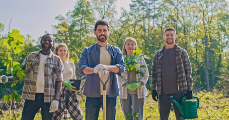 Happy caring people doing forestation work smiling and looking at camera. Cheerful attractive man...