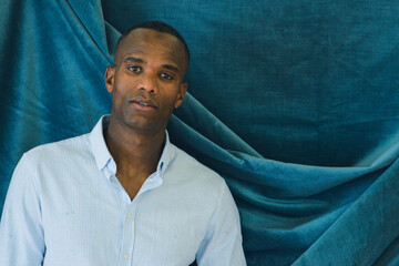 black young fit man standing over a blue velvet cloth