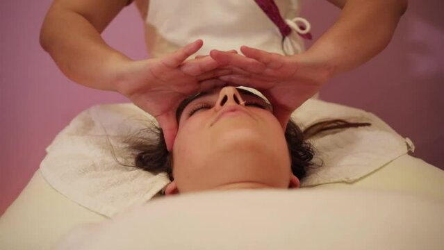 Masseur does head massage for young woman in thai spa salon